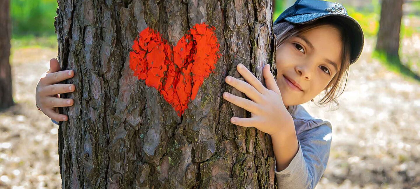 Kind hinter einem Baum mit Herz